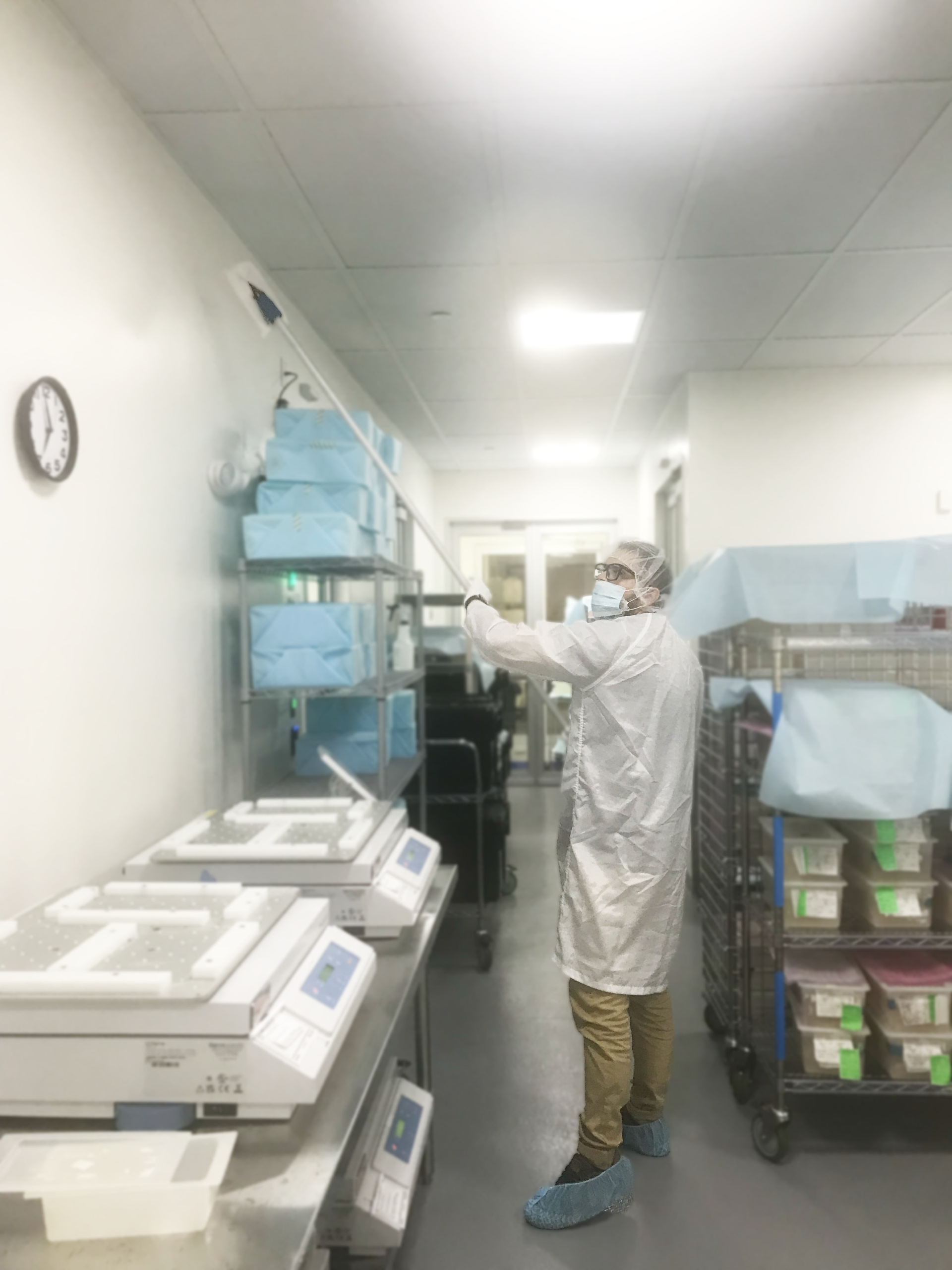 Technician in protective gear performing cleanroom ceiling and wall cleaning for contamination control by Transcend Maintenance.