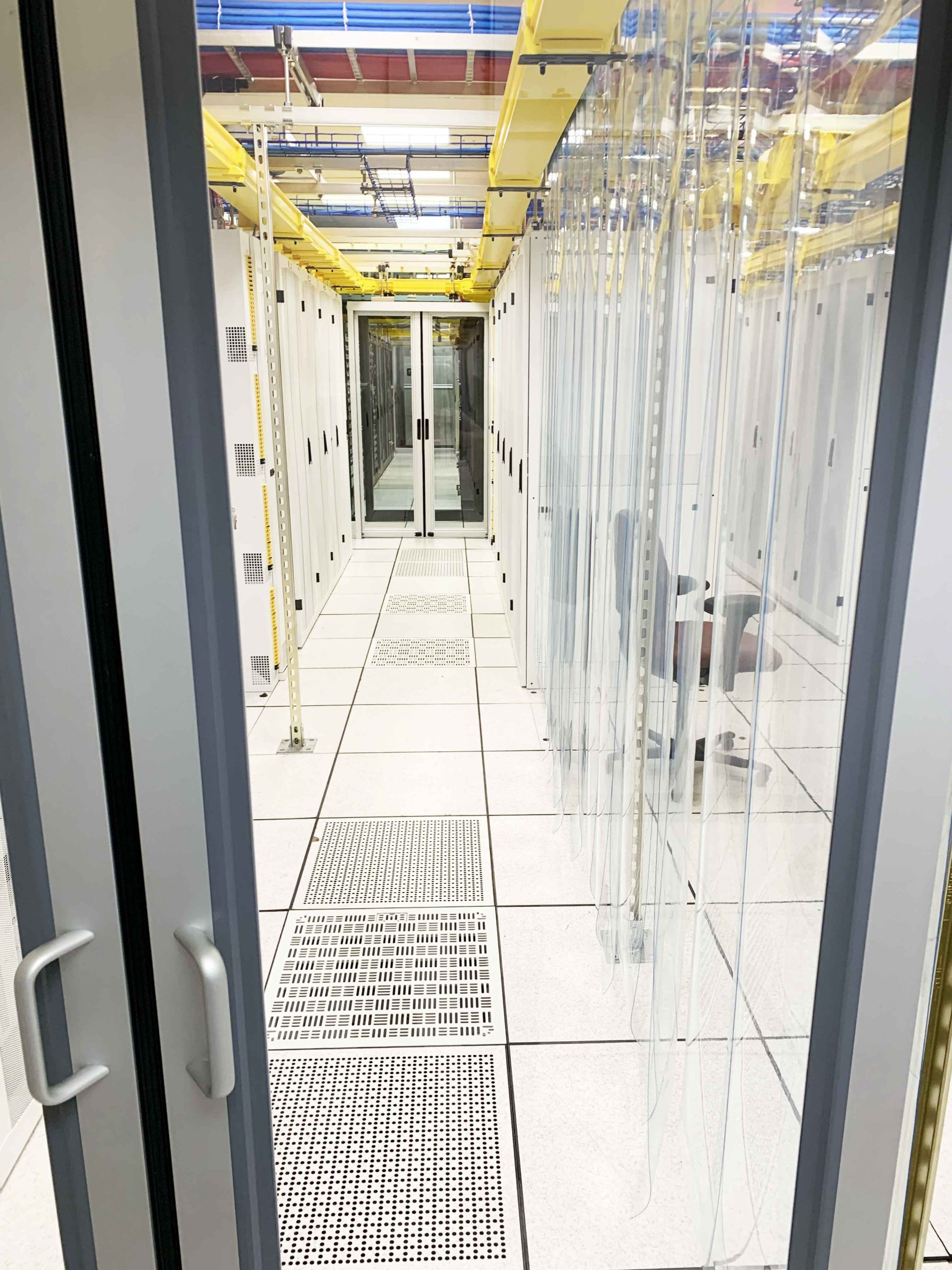 Spotless data center with polished white tile floors and organized server racks, maintained through professional cleaning services.