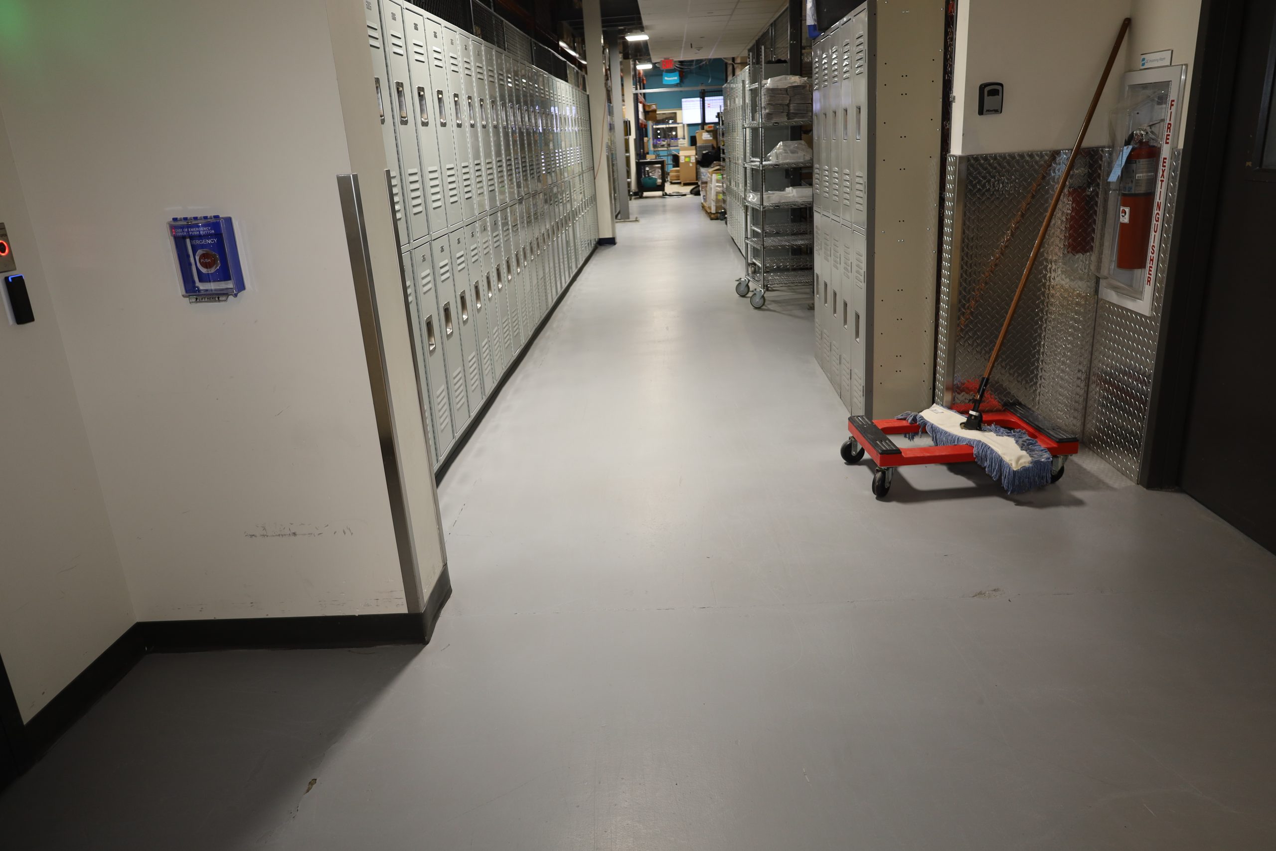 Industrial facility hallway with lockers and mop cart prepared for professional cleaning by Transcend Maintenance.