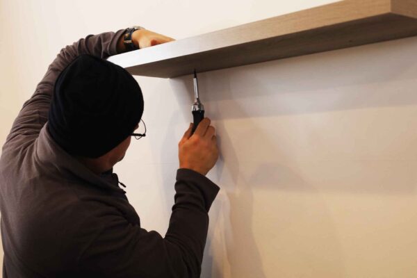Commercial handyman performing building maintenance by installing shelving, part of Transcend Maintenance facility services.